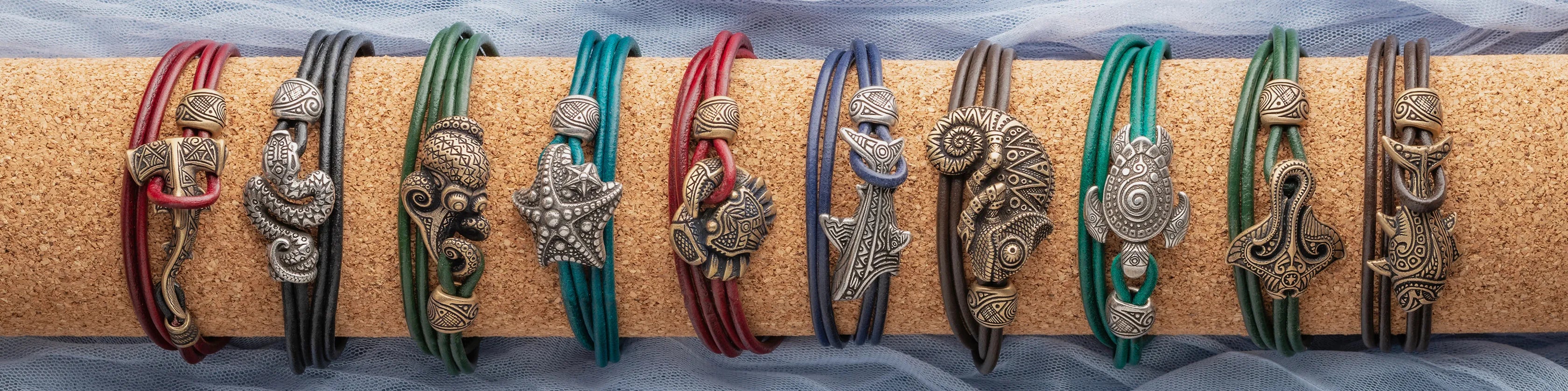 A row of colorful leather bracelets with metallic seahorse charms, displayed on a cork stand.