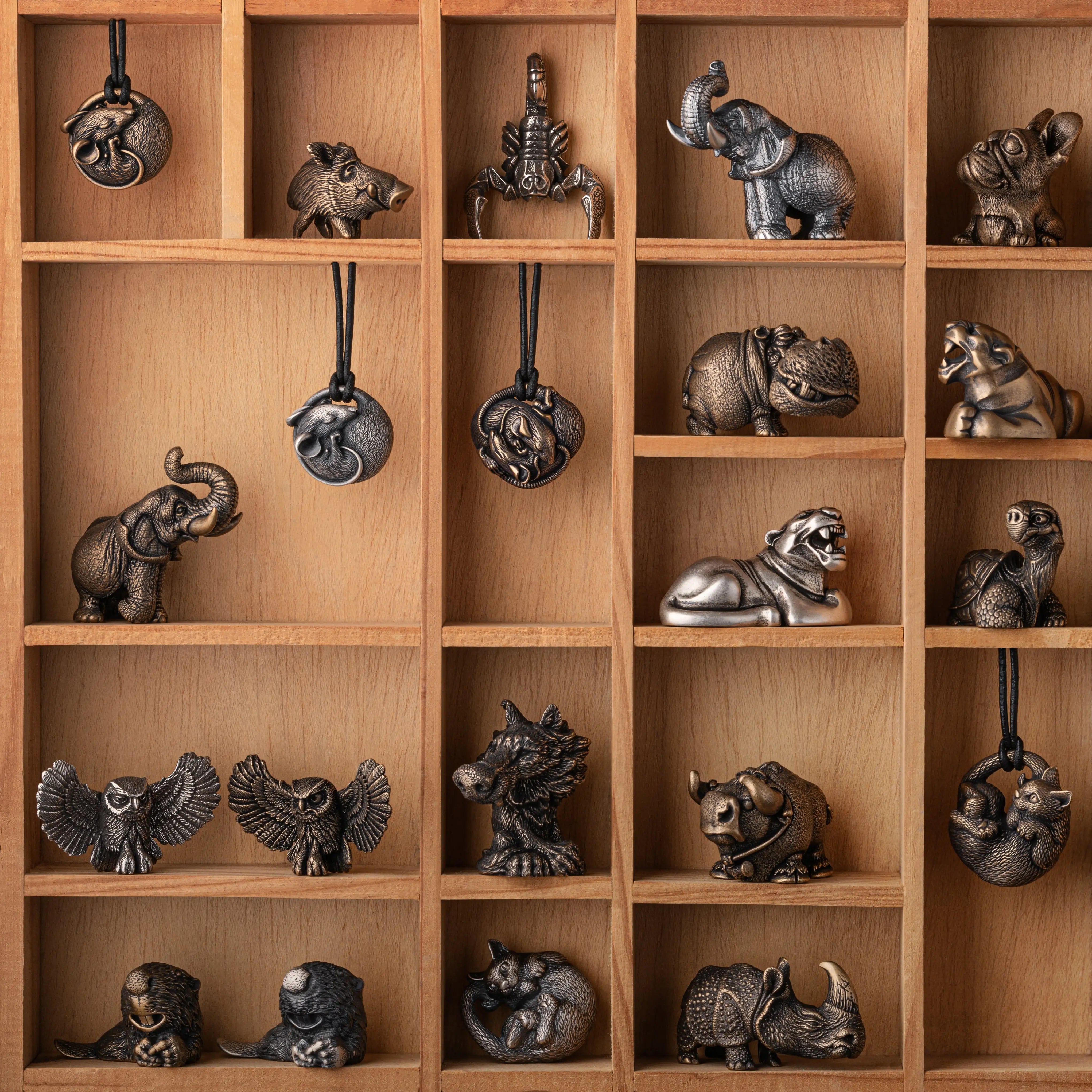 A wooden display shelf filled with small metallic animal figurines and hanging ornaments in various poses, including elephants, rhinos, owls, a scorpion, a monkey, and a turtle.